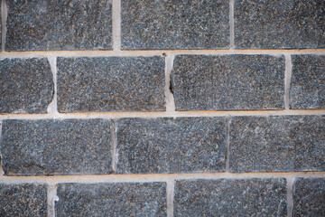 Wall of stones. Brick wall. Gray background with black geometric patterns. Black wall of rectangular stones, bricks. Part of a stone wall pattern for background, texture or text. close-up