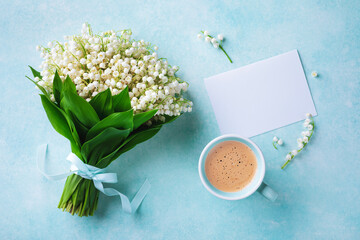 Coffee cup with spring bouquet of flowers lily of the valley and empty greeting card top view. Good...