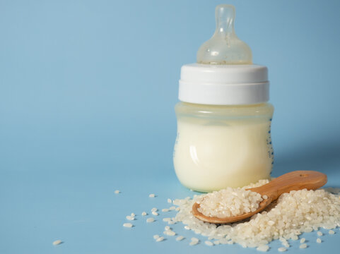 rice in a wooden spoon on the background of a baby bottle, baby milk rice drinking porridge .baby food concept, copy space