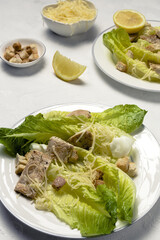 Homemade Caesar Salad with romanine, cheese, croutons, chicken, lemon and sauce