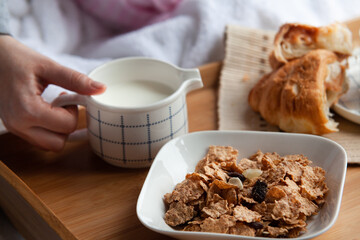 Healthy breakfast in bed served tray in bed with cornflakes and dried fruits and a cup of coffee with croissant. Good start to the day to have the right meal.