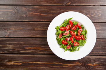 Fresh vegetable salad with tomatoes and arugula on wooden table, top view, healthy food