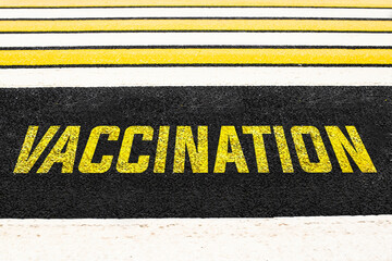 Fototapeta premium Pedestrian crossing across the road with the inscription VACCINATION on the asphalt. High quality photo