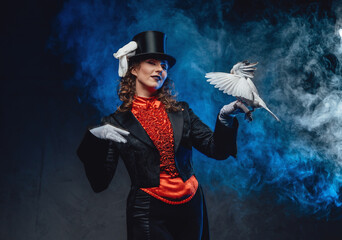 Elegant actress wearing dark clothing with trained doves in smoke