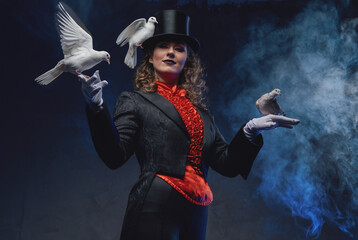 Spectacular portrait of a tricky woman wearing top hat with jacket posing with doves