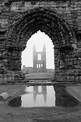 old stone arch framing tower with reflection in water 