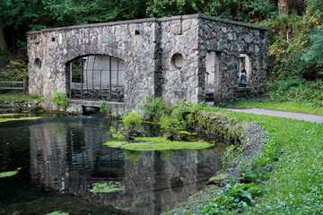 ruins of stone spring house reflected in water