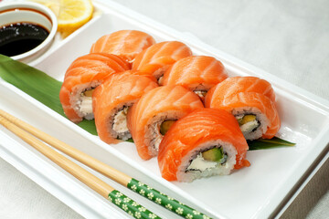 Philadelphia sushi made with fresh raw salmon, cream cheese and avocado. Rolls in a plastic container for delivery. Delicious healthy food.