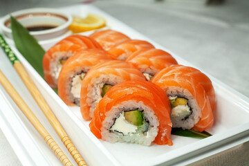 Philadelphia sushi made with fresh raw salmon, cream cheese and avocado. Rolls in a plastic container for delivery. Delicious healthy food.