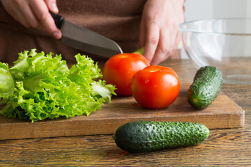 woman cutting fresh vegetables at home, making a salad