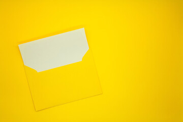 One yellow envelope with a blank white card. Yellow background.  Mockup with envelope and blank card. Space for text.