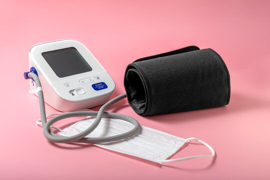 Tonometer. Automatic blood pressure monitor. Disposable mask. Pink background. High quality photo
