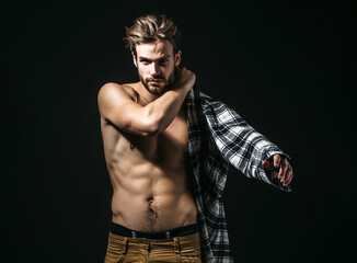 Sexy young handsome man wears plaid shirt on dark background.