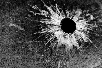 Broken glass with bullet hole, closeup. Abstract background, texture