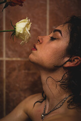 Almost naked young women holding a white rose in bathroom