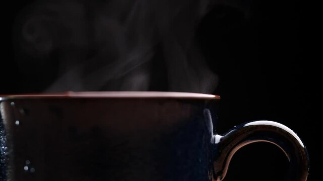Coffee cup with natural steam smoke of coffee on wooden table, black background with copy space, slow motion. Hot Coffee Drink Concept.