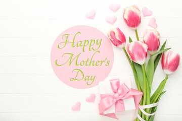 Mother's Day concept. Tulip flowers with gift box and pink hearts on white wooden table