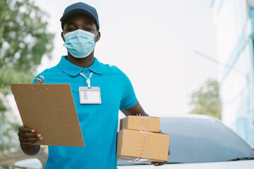 African delivery man holding boxs and cardboard with wearing face mask