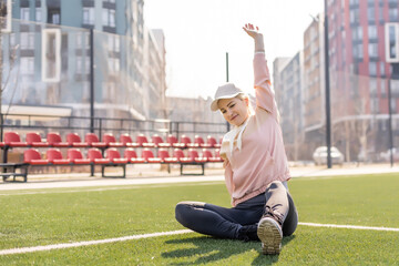 Fototapeta na wymiar Sport. Fitness Girl Doing Stretching Workout. Fashion Sporty Woman With Strong Muscular Body Training. Fit Female Stretching At Outdoor Stadium.