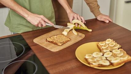 Young same sex male pair cutting banana for toast