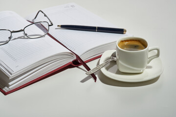 cup of aromatic espresso coffee diary glasses pen on white background. Selective focus. Selective focus.
