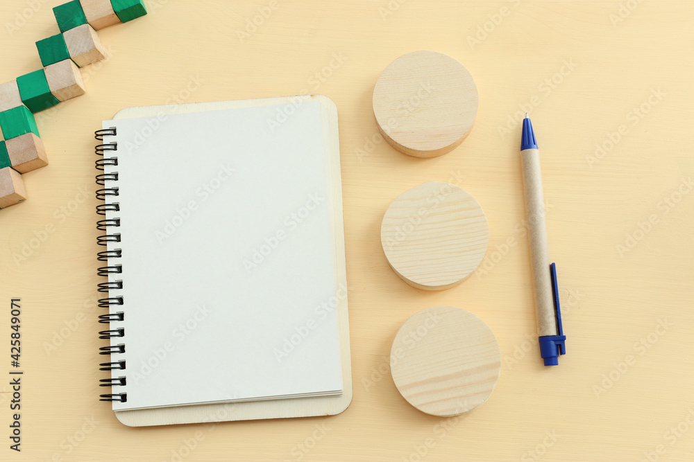 Poster top view image of open notebook with blank pages on wooden yellow pastel background. ready for addin