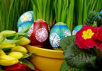Beautiful hand painted easter eggs with spring flowers close-up stock images. Easter decoration with colored eggs and fresh flowers photo. Traditional unique easter eggs images