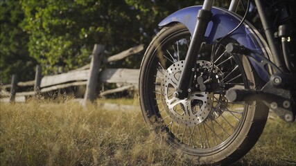 old retro motorcycle and beautiful sunset sky background. Front wheel of a motorcycle on the field.