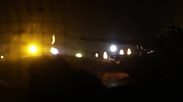 War Concept. Armored vehicle silhouette fighting scene on war foggy sky background at night. American tank moving in destroyed city. Slider shot