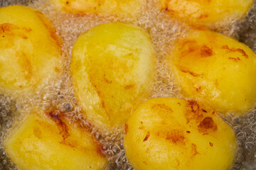 Golden potatoes are fried in boiling oil in a cauldron