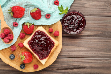 Toast with jam and ripe berries on wooden table