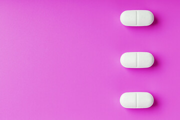 White Ecstasy pills in a row on a pink background, isolate.