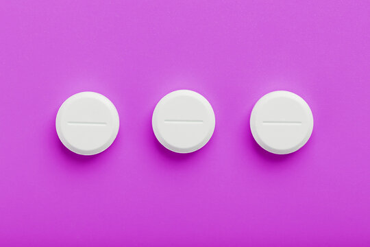 White Ecstasy pills in a row on a pink background, isolate.