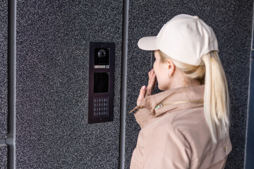 Close up the female hand presses the doorphone button. The girl is calling the intercom. Means of communication or notification of arrival and security of the entrance inside