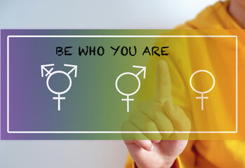Gender confusion in teenager boy.  A teenage boy pointing at the gender symbols male, bigender and...