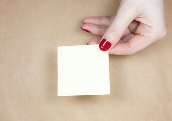 Blank yellow To Do List Sticker in woman hand. Close up of reminder note paper on kraft background....