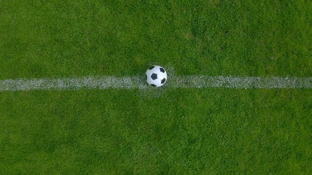 Drone footage of a professional football soccer player putting the ball at the center point of a stadium. 4k