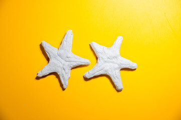 Fototapeta na wymiar Pair of the plaster starfishes on yellow background.