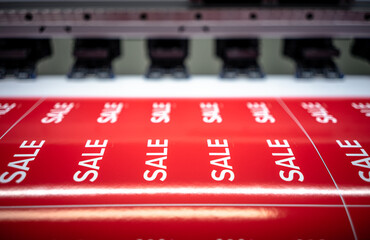 Printing of red stickers with the inscription sale on the printing press