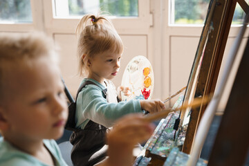 Little boy and girl draw a picture on an easel