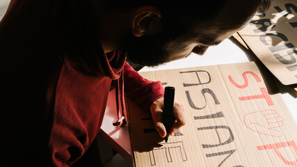 Man drawing posters protest against racism at home
