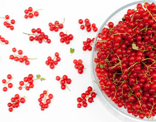 A large bowl of red currants with juicy bunches scattered around.