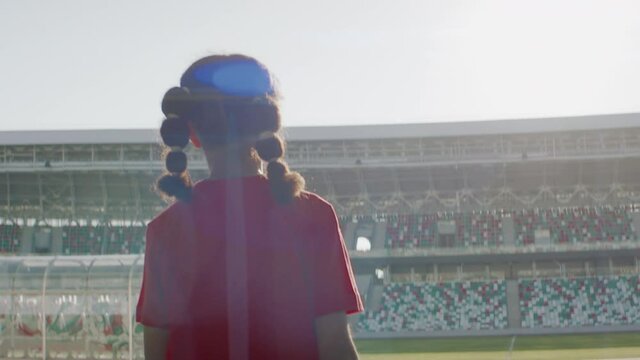 HANDHELD TRACKING African American Black child girl entering the field of huge soccer football stadium, spreading hands, dreaming of becoming professional player, soccer star. Women sport concept