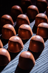 .Chocolate candies stuffed with strawberry sauce cooling on a black wooden countertop