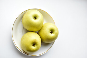 Three green apples on a white plate