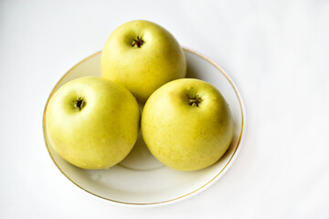 Three green apples on a white plate