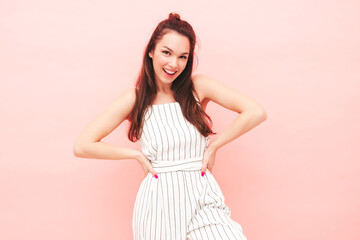 Portrait of young beautiful smiling female in trendy summer hipster overalls clothes. Sexy carefree woman posing near pink wall in studio. Positive model having fun indoors. Cheerful and happy