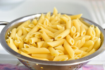 Freshly washed Italian pasta in a colander in the kitchen