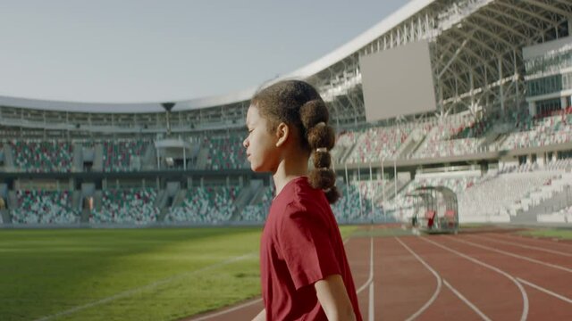 Portrait of African American Black child girl walking onto the field of huge soccer football stadium, spreading hands, dreaming of becoming professional player, soccer star. Women sport concept