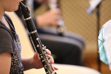 Close-up of a baby girl playing a black clarinet mouthpiece in her mouth fingers on silver flaps in a music lesson at school. The concept of children's music education and development